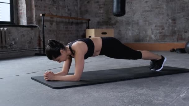 Jonge mooie vrouw doet planken in de sportschool. Begrip sport en gezonde levensstijl.  - Video