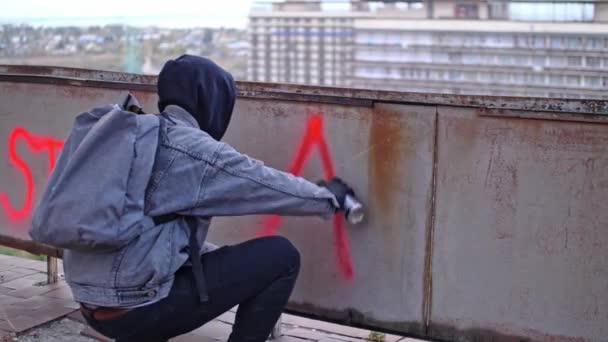 Процесс создания граффити анархии молодым протестующим в капюшоне - Кадры, видео