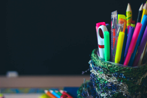 Színes ceruzák és tollak egy sötét iskolai táblán. A táblán helyet a fénymásoláshoz. - Fotó, kép