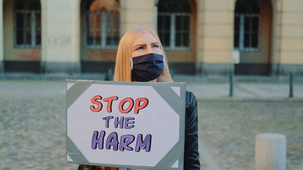 Blonde Frau in Schutzmaske protestiert, um Schaden zu verhindern, indem sie Dampfer hält - Foto, Bild