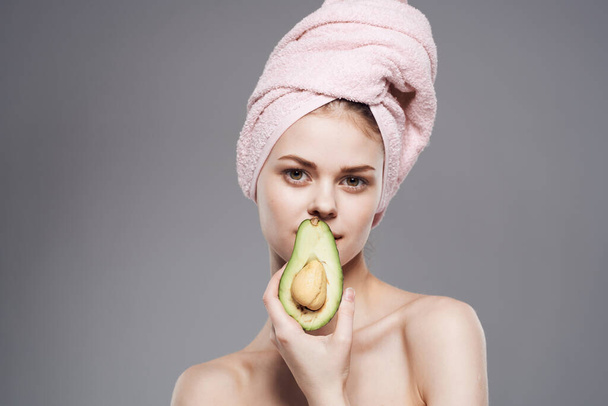 Cheerful woman cropped view of naked shoulders with towel on avocado head - Photo, Image