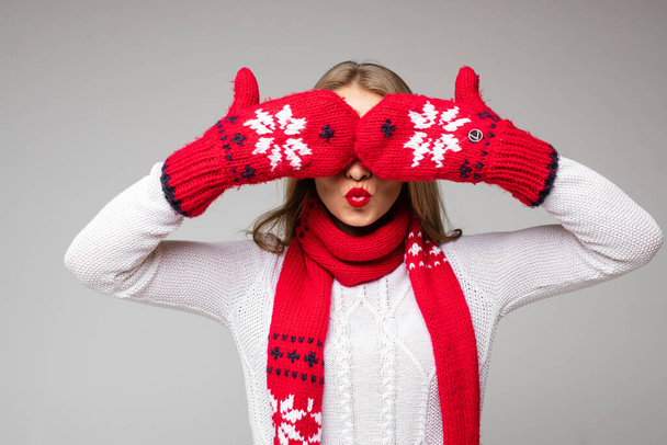 Κορίτσι που καλύπτει τα μάτια με γάντια του χειμώνα. Απομόνωση σε γκρι. - Φωτογραφία, εικόνα
