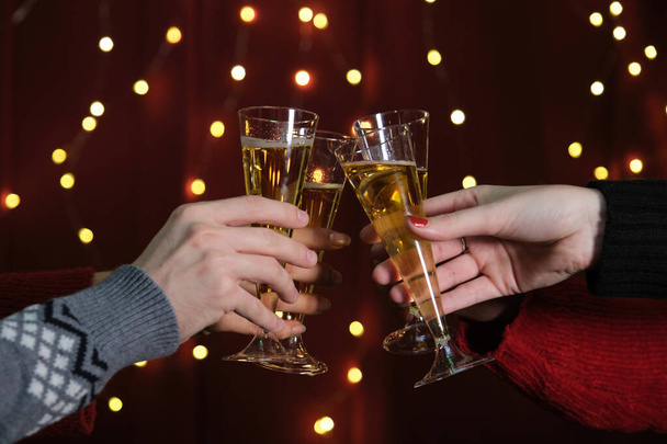 Un groupe d'amis méconnaissables à une fête de Noël portant un toast, des lumières en arrière-plan. Fête de Noël. - Photo, image