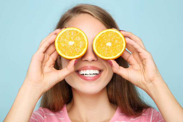Young girl with fresh orange fruit on blue background - Foto, Bild