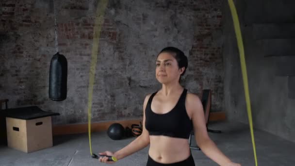 Młoda Hinduska skakanka ubrana w strój sportowy Black Top i legginsy, jest w siłowni - Materiał filmowy, wideo