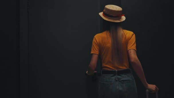 młoda kobieta w słomkowym kapeluszu spacerująca z bagażem w pokoju hotelowym - Materiał filmowy, wideo