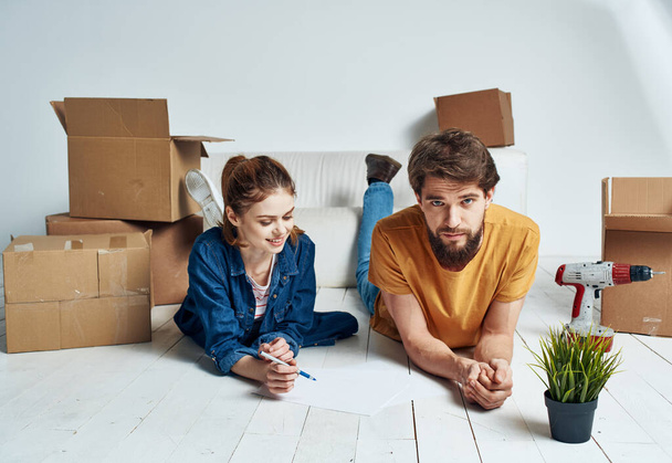 wzruszający remont szczęśliwy mężczyzna i kobieta na podłodze w nowym mieszkaniu z pudełkami - Zdjęcie, obraz