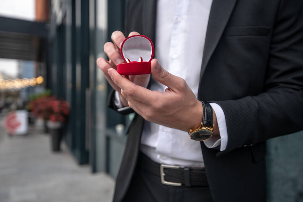 Close up picture of mans hands holding a box with engagement ring - Foto, Imagem