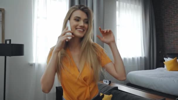 веселая женщина разговаривает на смартфоне в гостиничном номере  - Кадры, видео