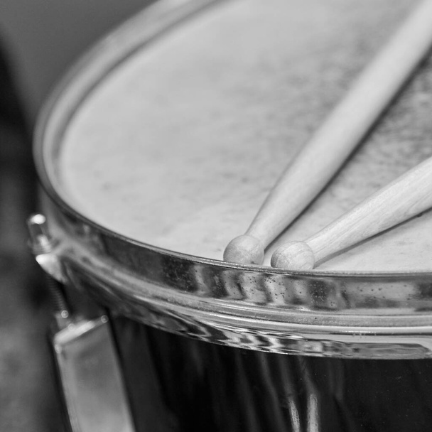 Twee houten drumstokken liggen op de trommel, zwart-wit foto - Foto, afbeelding