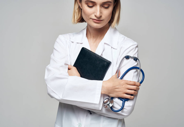 woman doctor with stethoscope and medical gown documents in hands - Foto, afbeelding