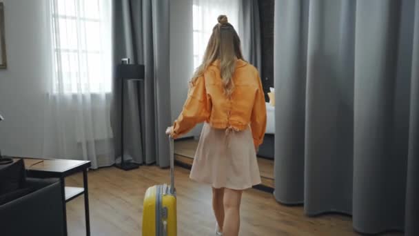 nuori matkustaja mekko ja takki kävely matkalaukku hotellihuoneessa  - Materiaali, video