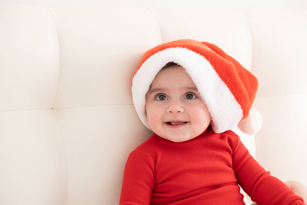 portrait baby girl 6 month in red bodysuit and Santa hat. minimalist. - Foto, afbeelding