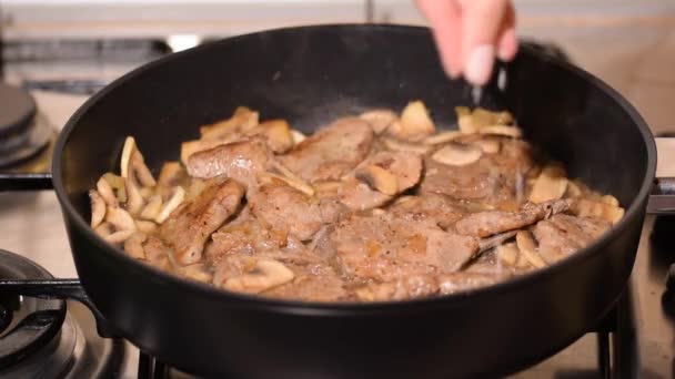 Spruzza carne di maiale con sale. Carne di maiale di cottura con funghi. Chef preparare delizioso pranzo di maiale. - Filmati, video