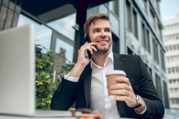 Handsome young businessman having coffee and talking on the phone - Φωτογραφία, εικόνα