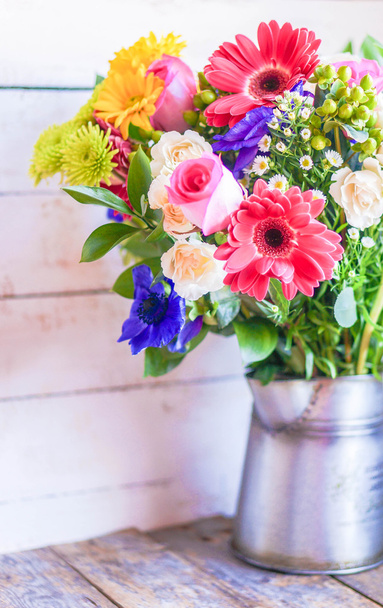Colorful bouquet of spring flowers in vintage vase on rustic wooden background - Photo, Image