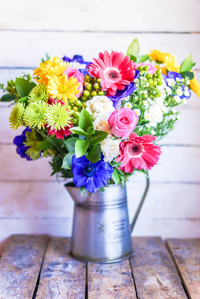 Colorful bouquet of spring flowers in vintage vase on rustic wooden background - Foto, afbeelding
