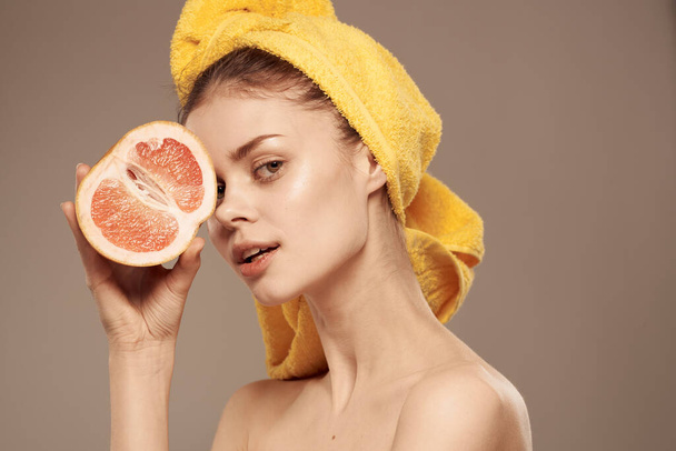 Ładna kobieta z ręcznikiem na głowie czysta skóra obnażone ramiona owoce cytrusowe w rękach - Zdjęcie, obraz