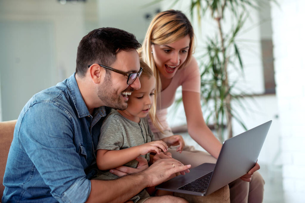 Família jovem procurando filmes no laptop juntos em casa.  - Foto, Imagem