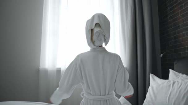 widok z tyłu kobieta w szlafroku rozciągające się w pokoju hotelowym  - Materiał filmowy, wideo