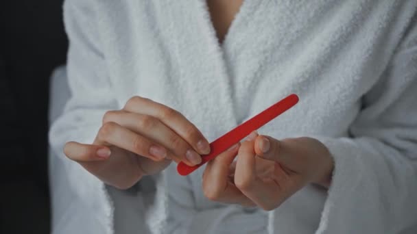 νεαρή γυναίκα με μπουρνούζι γυαλίζει τα νύχια στο ξενοδοχείο  - Πλάνα, βίντεο