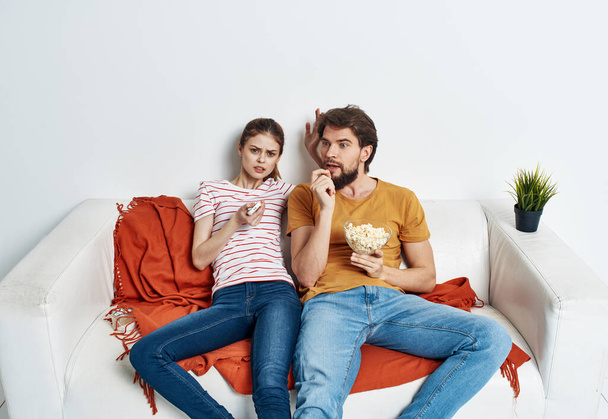 Coppia innamorata di popcorn e guardare la TV mentre sul divano al chiuso - Foto, immagini
