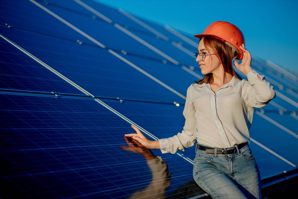 Beautiful young engineer standing near solar panels outdoors, Green Energy Concept. - Photo, image