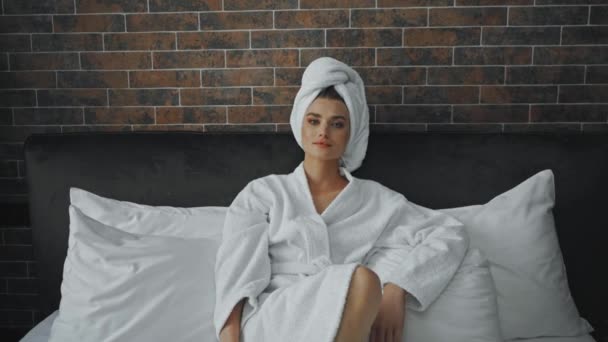 Bornozlu genç bir kadın ve otel odasında beyaz bir havlu. - Video, Çekim