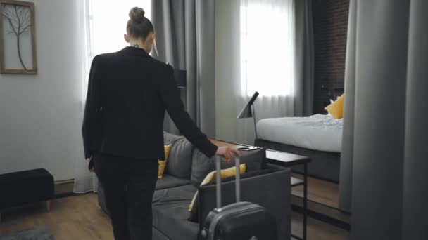 businesswoman in formal wear walking in hotel room with luggage - Záběry, video