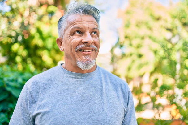 Moyen Age hispanique homme aux cheveux gris souriant heureux debout au parc. - Photo, image