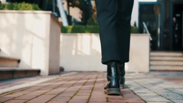 Siguiendo los pies de los hombres jóvenes hombres de negocios stulish caminando fuera de la ciudad urbana en ángulo bajo - Imágenes, Vídeo
