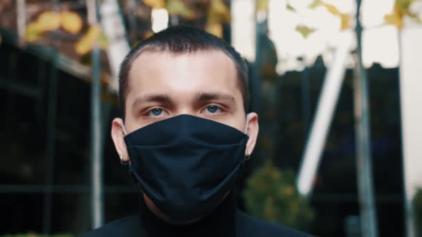 Protection Face Maskを身に着けている肖像画男は、カメラを見てCOVID-19コロナウイルス感染パンデミックウイルス感染症男性観光流行空気健康病気スローモーション - 映像、動画