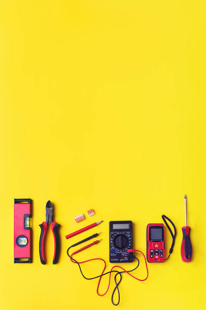 Conjunto de herramientas de electricista sobre fondo amarillo. Composición plana con herramientas de electricista y espacio para texto de fondo amarillo - Foto, imagen