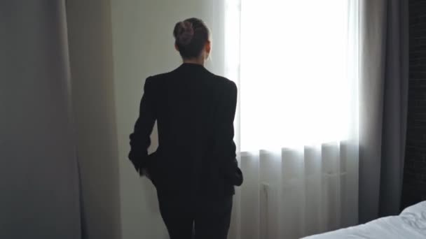 zakenvrouw lopen met de handen in zakken en kijken naar venster - Video
