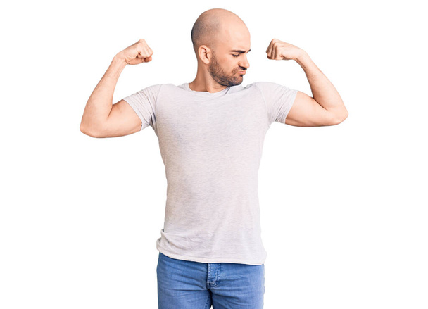 Joven hombre guapo con camiseta casual mostrando los músculos de los brazos sonriendo orgulloso. concepto de fitness.  - Foto, imagen