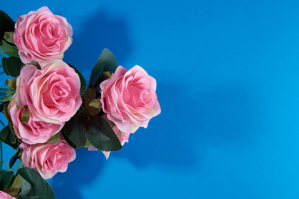 sztucznie różowe róże na niebieskim tle.pocztówka - Zdjęcie, obraz