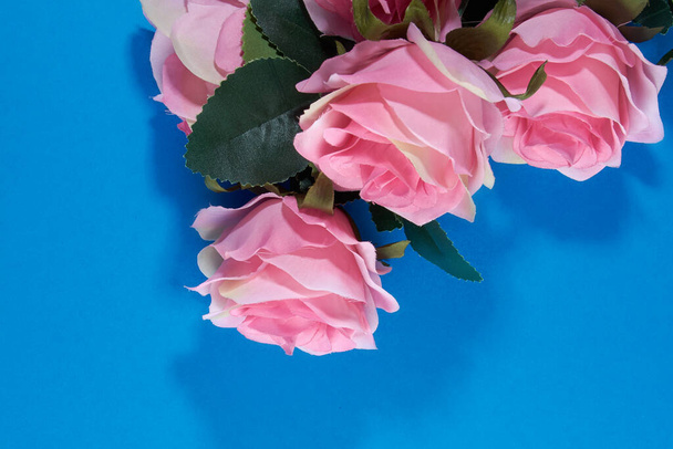 artificial pink roses on a blue background.postcard - Photo, Image