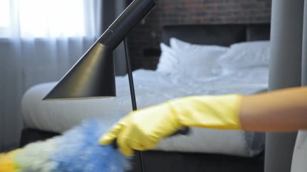 jeune femme de chambre nettoyage poussière sur lampe avec brosse  - Séquence, vidéo