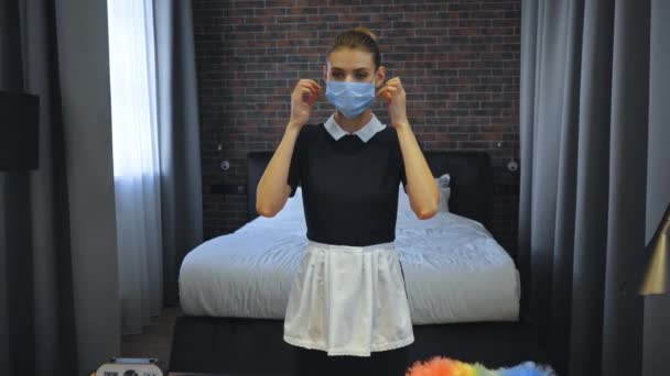junges Zimmermädchen trägt medizinische Maske im Hotelzimmer - Filmmaterial, Video