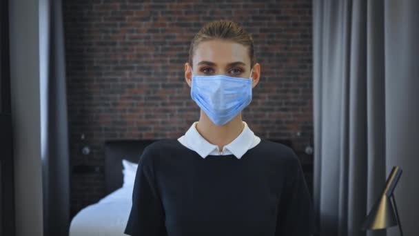 jong kamermeisje in medisch masker op zoek naar camera - Video