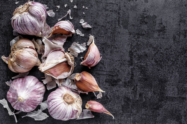 natural food, heads of garlic on a black background. Top view. Copy space. - Fotó, kép