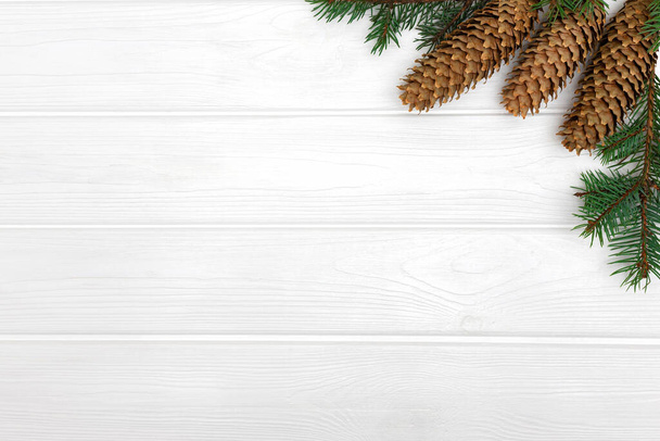 Tannenzapfen und Äste auf weißem Holzgrund. New Year Plakatvorlage, Kopierraum  - Foto, Bild