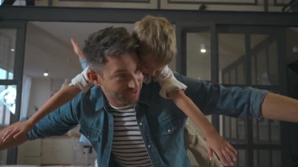 Χαρούμενος πατέρας με απλωμένα τα χέρια να κουβαλάει το γιο του στο σπίτι - Πλάνα, βίντεο