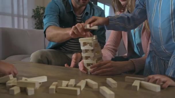 Vader in gesprek met familie tijdens blokken hout toren spel instorten op tafel - Video