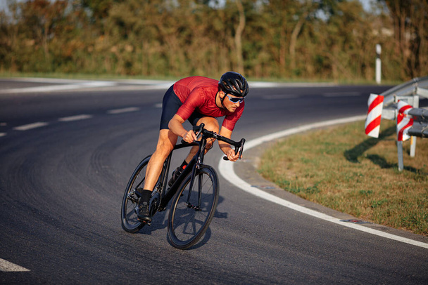 Hezký mladík jezdící na kole v ochranné přilbě a zrcadlových brýlích. Aktivní muž ve sportovním oblečení se připravuje na závody na čerstvém vzduchu. - Fotografie, Obrázek