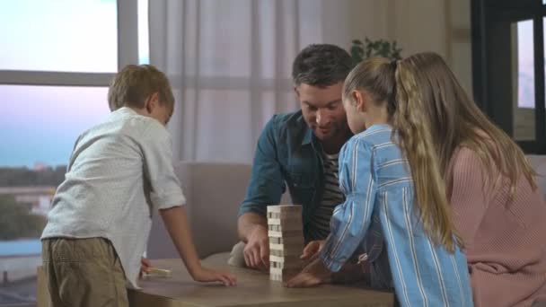 Feliz familia jugando bloques torre de madera juego en la sala de estar en casa - Imágenes, Vídeo