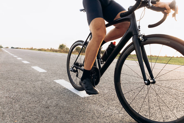 Professional cyclist in sport clothing riding bike on paved road, close up. Natural landscape. Concept of healthy and active lifestyle. - Foto, Imagen