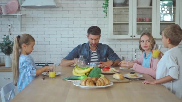 Οικογενειακό πόσιμο χυμό, τρώει τηγανίτες και μιλάμε κατά τη διάρκεια του πρωινού στην κουζίνα - Πλάνα, βίντεο
