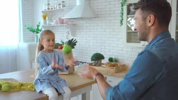 Szczęśliwy ojciec i córka rzucając zielone jabłka do siebie w kuchni  - Materiał filmowy, wideo