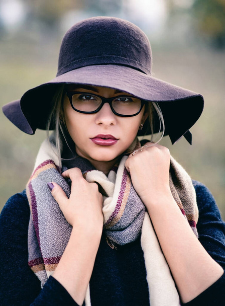 Κομψή γυναίκα με γυαλιά και καπέλο με μεγάλο φουλάρι. Η έννοια των φθινοπωρινών ρούχων. - Φωτογραφία, εικόνα